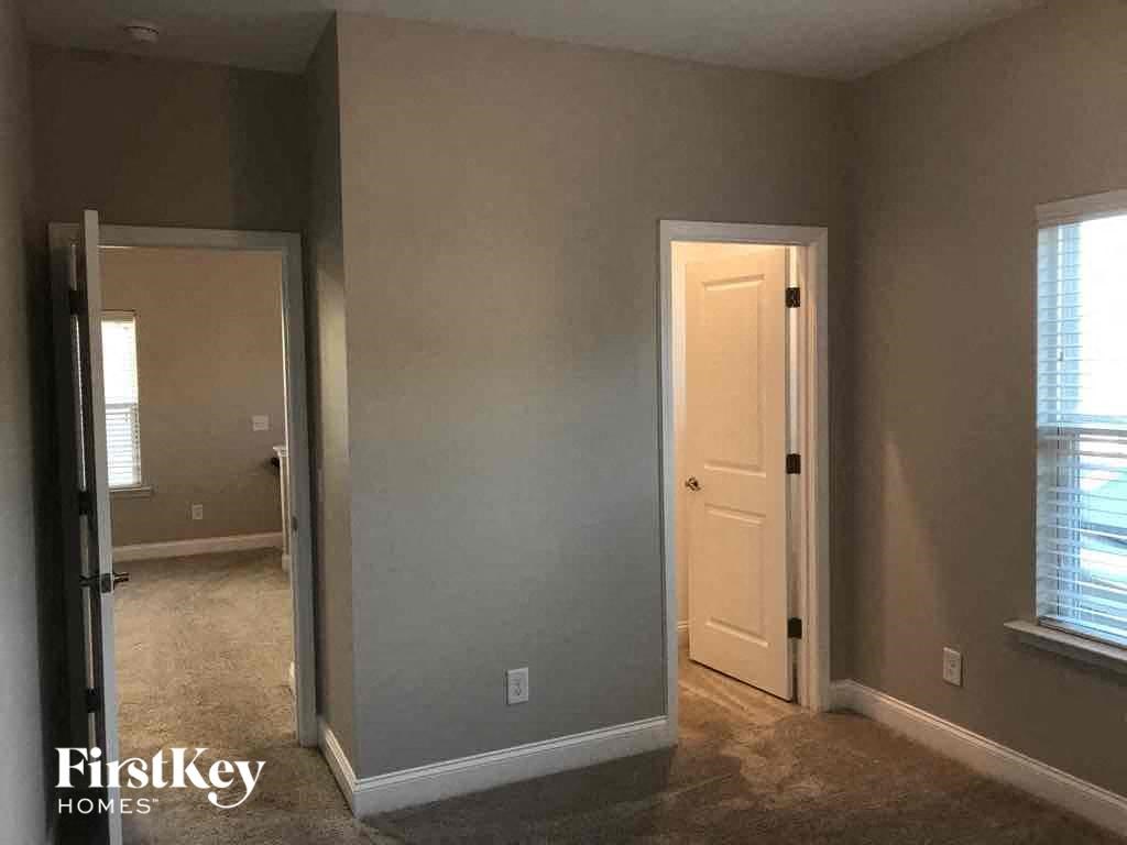 an empty room with a door open to a hallway and a door to a bedroom