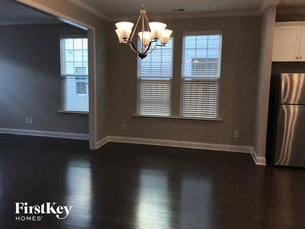 an empty dining room with a chandelier and three windows