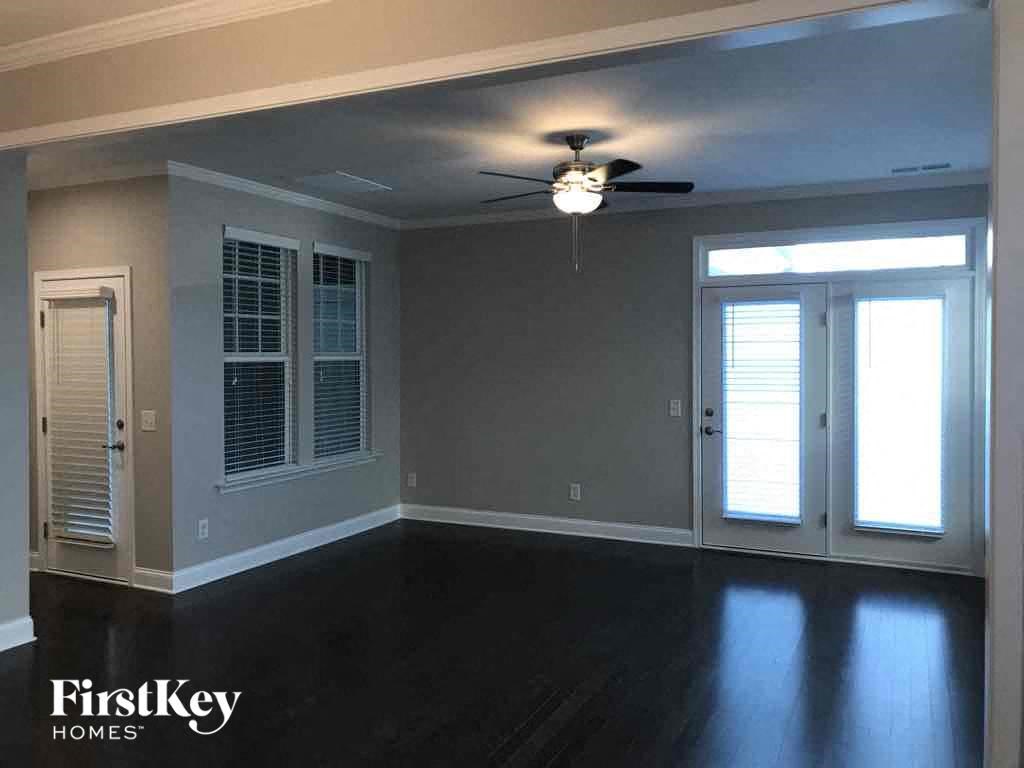 an empty living room with a ceiling fan and window
