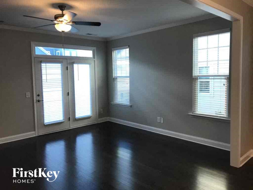 an empty living room with a ceiling fan and windows