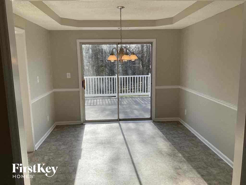 an empty living room with a patio door and a chandelier