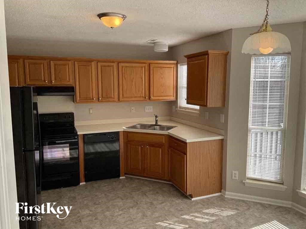 an empty kitchen with wooden cabinets and black appliances