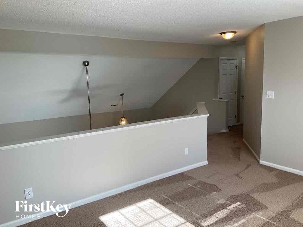 an empty living room with a white wall and carpeted floor