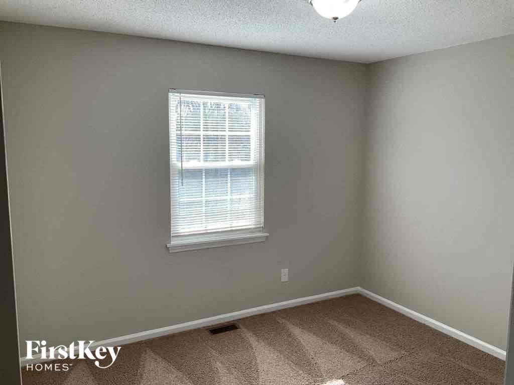 an empty bedroom with a window and a carpeted floor