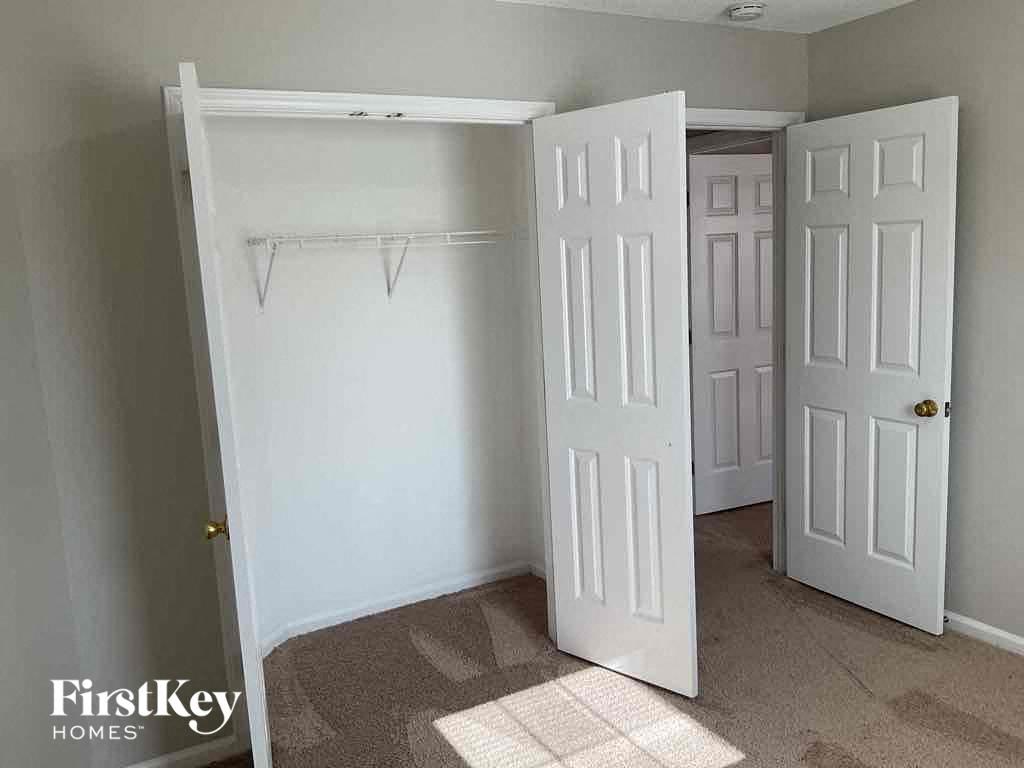 an empty closet in a bedroom with two white closet doors and a white closet door