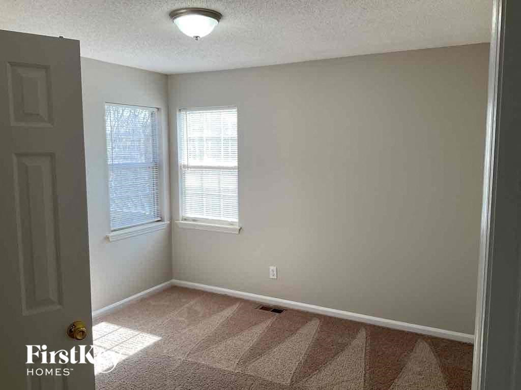 an empty room with a door and two windows