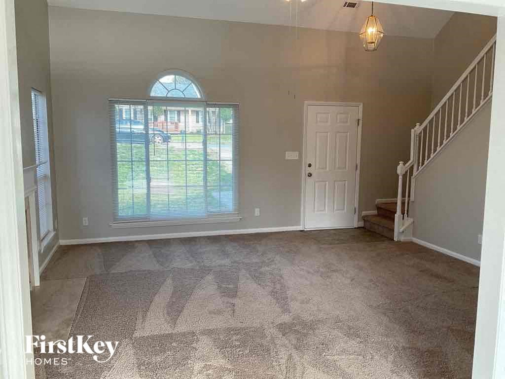 an empty living room with a staircase and a large window