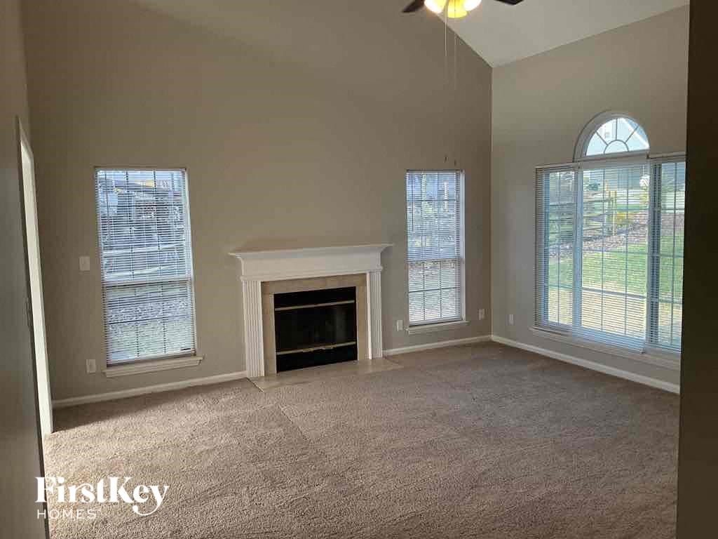 an empty living room with a fireplace and three windows
