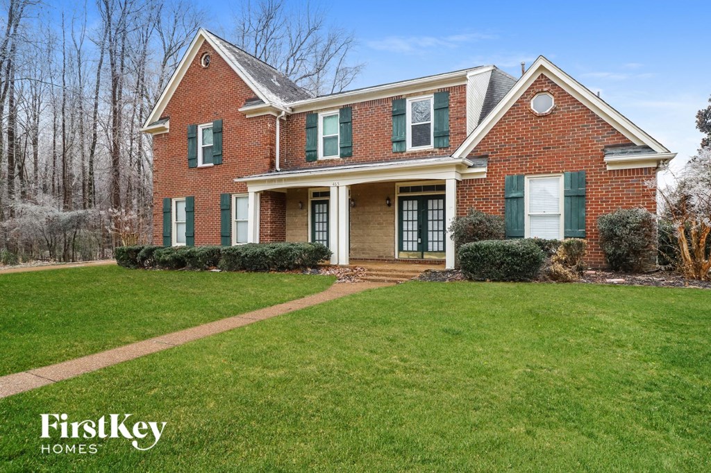 a brick house with green shutters and a lawn