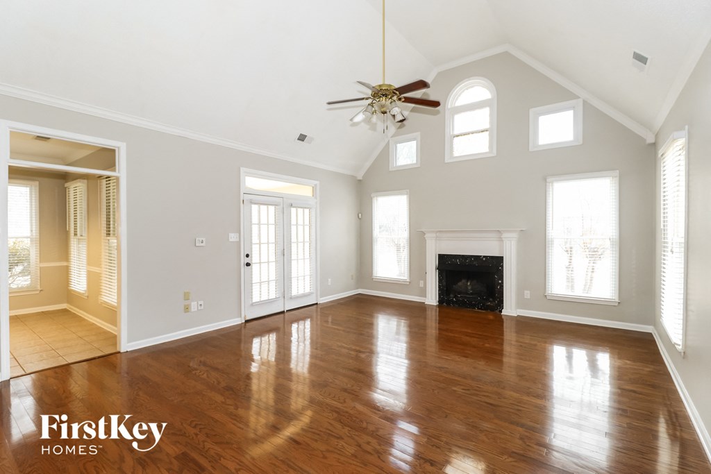an empty living room with a ceiling fan and a fireplace