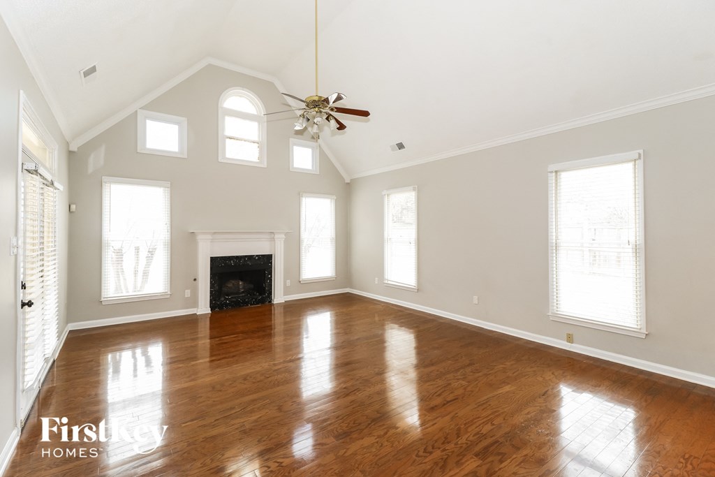 an empty living room with a ceiling fan and a fireplace