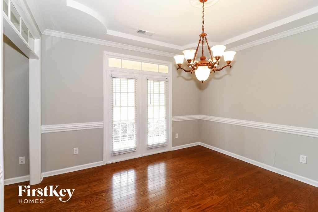 an empty dining room with wood floors and a chandelier