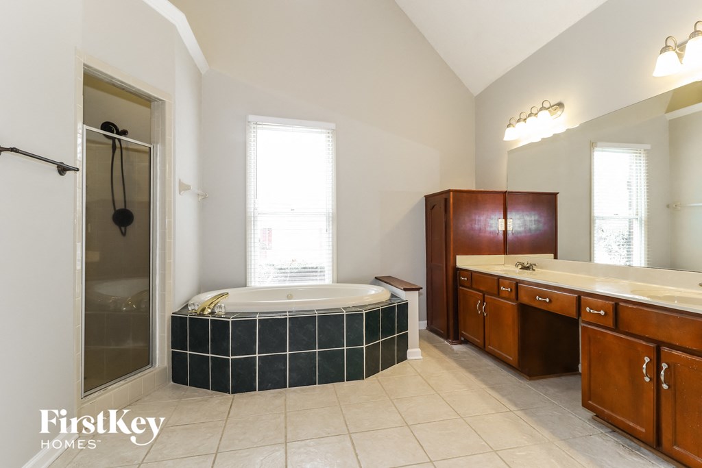a bathroom with a tub and two sinks and a shower