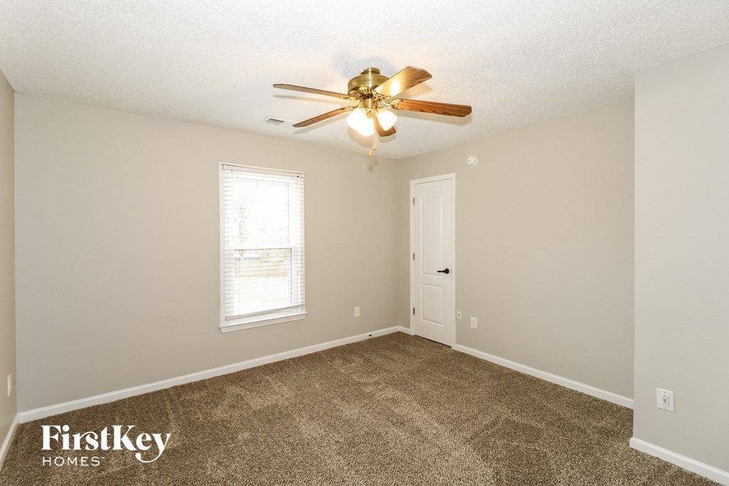 a living room with carpet and a ceiling fan