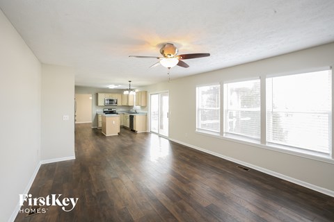 A spacious living room with wood flooring and a ceiling fan.