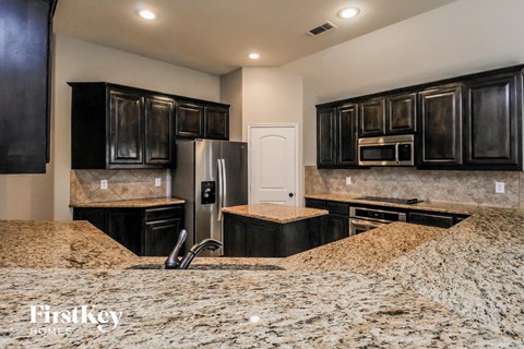 a kitchen with granite counter tops and black cabinets and stainless steel appliances