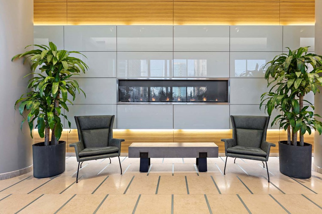 two chairs and a table in a lobby with plants
