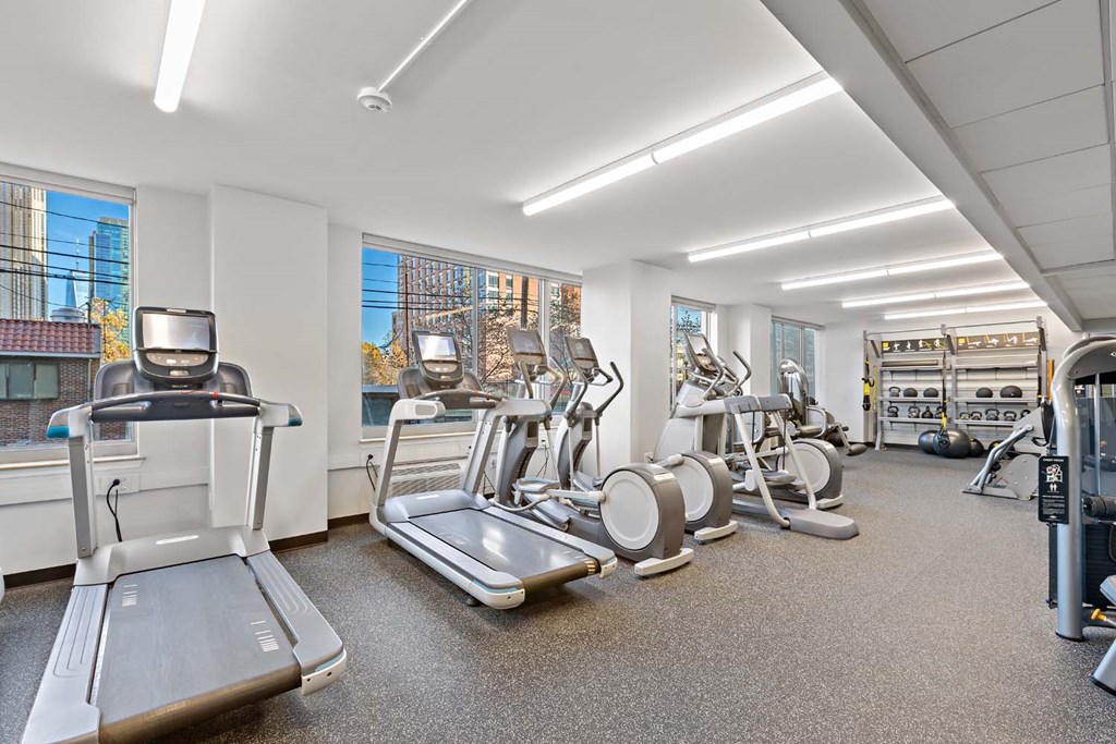 a gym with cardio equipment and windows in a building