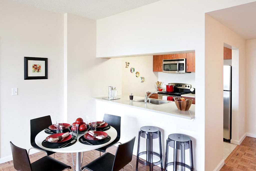 a dining room and kitchen with a table and stools