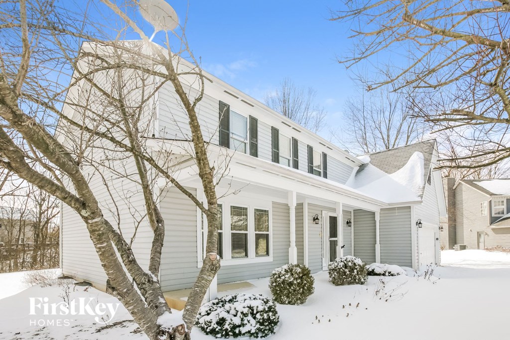 A white house with a snowy front yard.