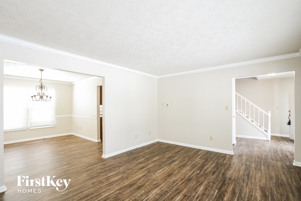 A room with wooden floors and white walls, with a chandelier hanging from the ceiling.