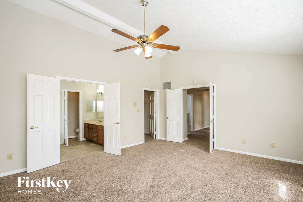 A spacious room with a ceiling fan and a carpeted floor.