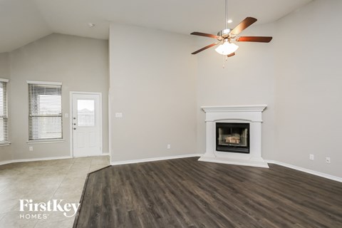 A spacious living room with a fireplace and a ceiling fan.
