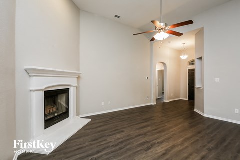 A spacious room with a fireplace and a ceiling fan.