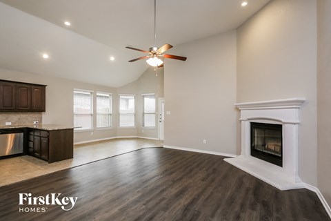 A spacious living room with a fireplace and a ceiling fan.