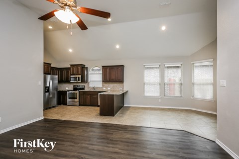A spacious kitchen and living room with a ceiling fan and recessed lighting.