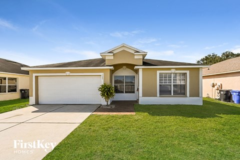 a beige house with a white garage door and a lawn
