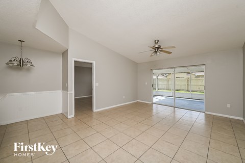 an empty living room with a ceiling fan and a sliding glass door to a pool