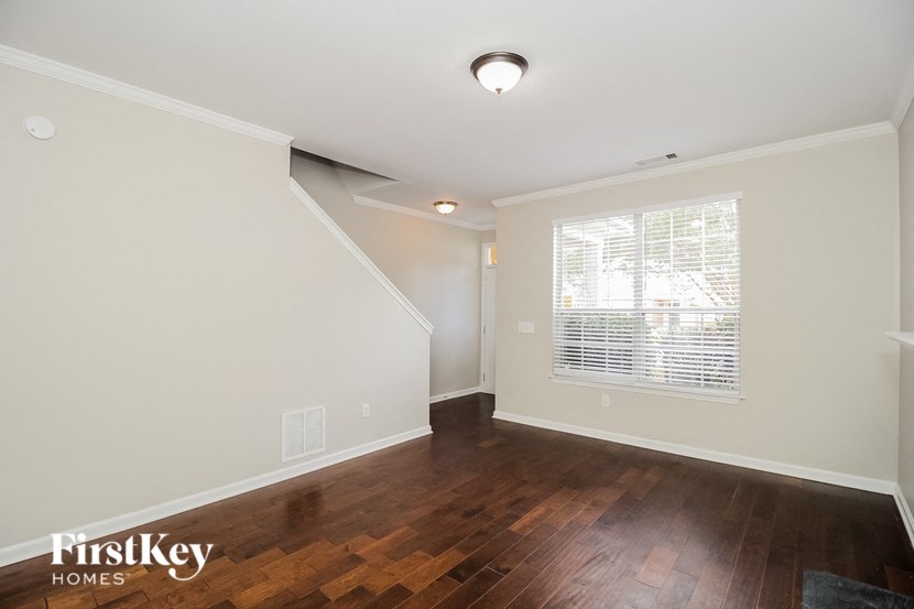 A room with wooden floors and a staircase leading to another room.