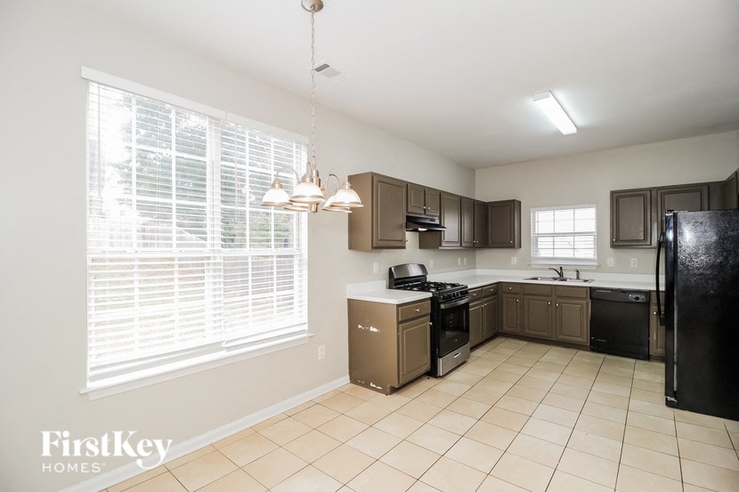 A kitchen with a black refrigerator and brown cabinets.