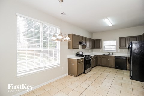 A kitchen with a black refrigerator and brown cabinets.