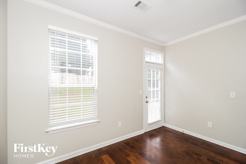 A room with a wooden floor and a window with blinds.