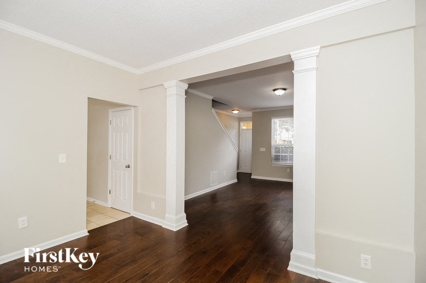 A room with wooden floors and white walls, with a doorway leading to another room.