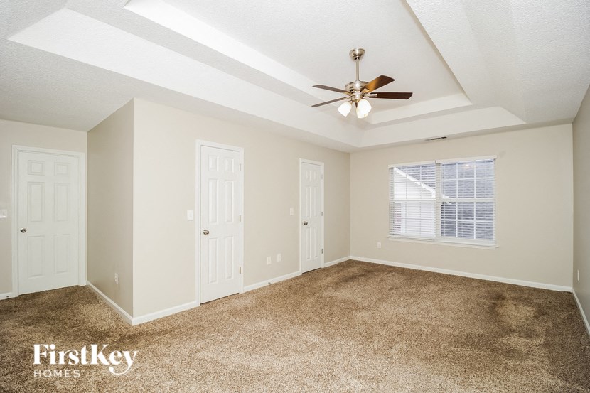 A spacious room with a carpeted floor and a ceiling fan.