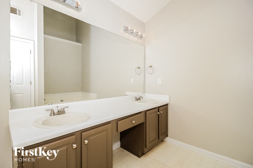 A bathroom with a white counter top and brown cabinets.