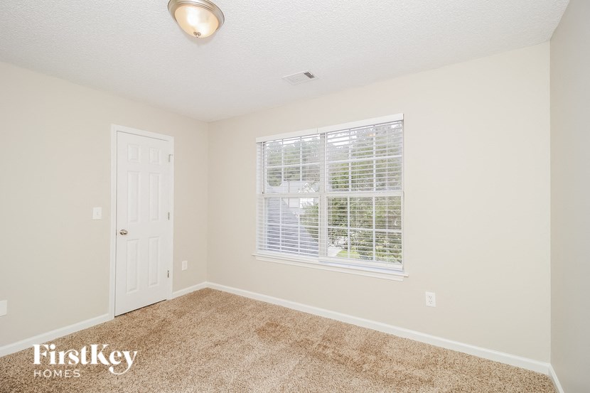 A room with a carpeted floor and a window with blinds.