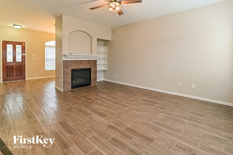 A spacious living room with a fireplace and a ceiling fan.