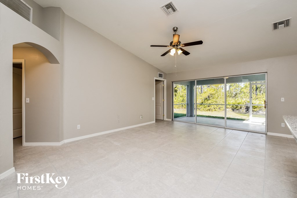 A spacious room with a ceiling fan and sliding glass doors leading to a garden.