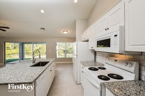 A kitchen with white appliances and cabinets.