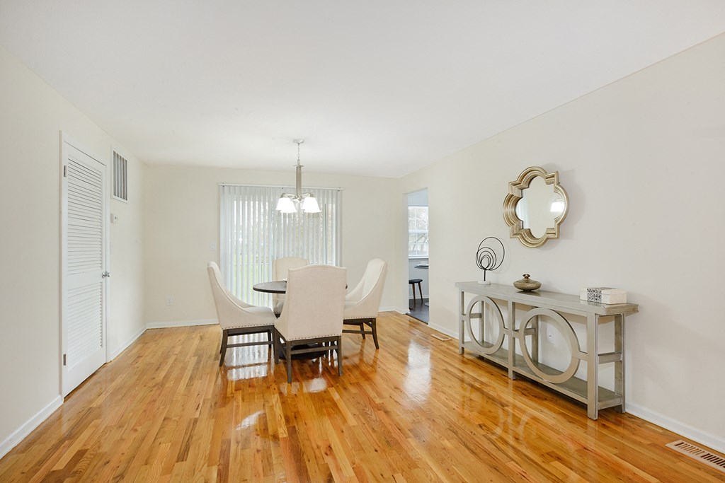 a dining room with a table and chairs and a mirror on the wall