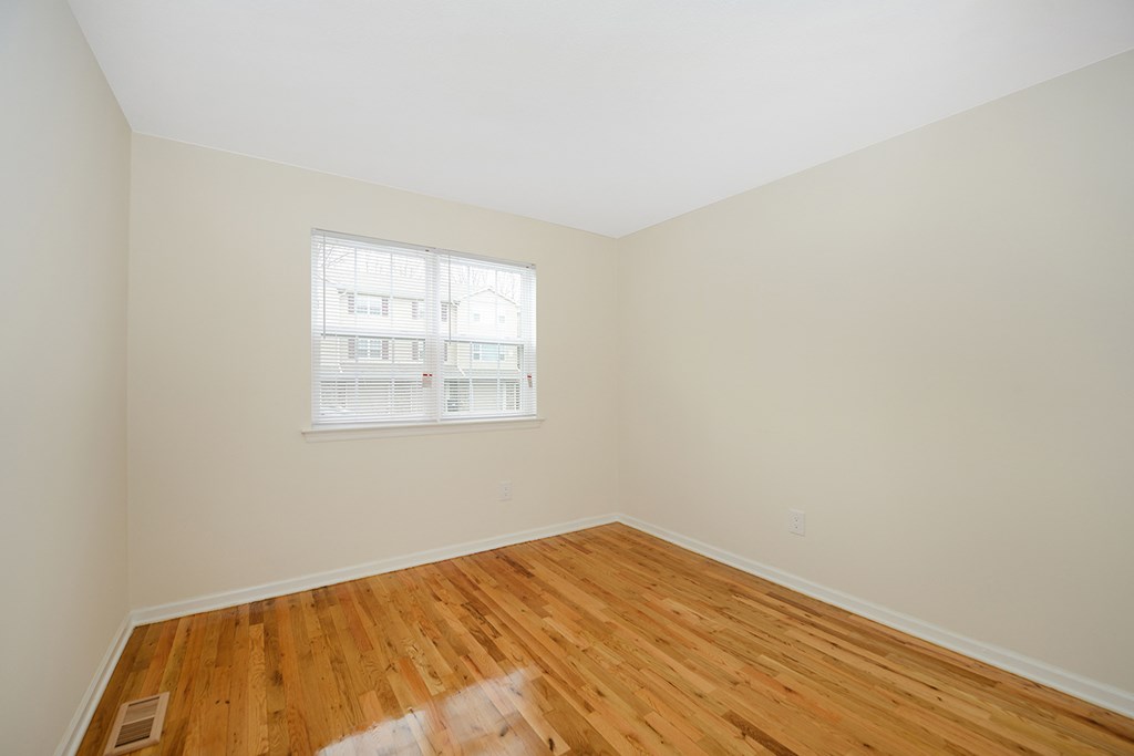 an empty room with wood floors and a window