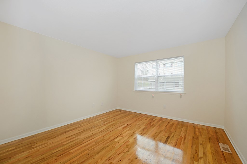 an empty room with wood floors and a window