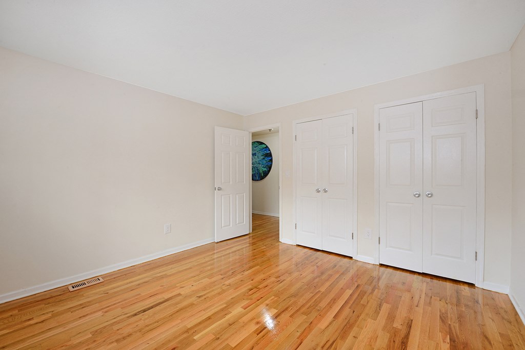 a bedroom with three closets and a hard wood floor