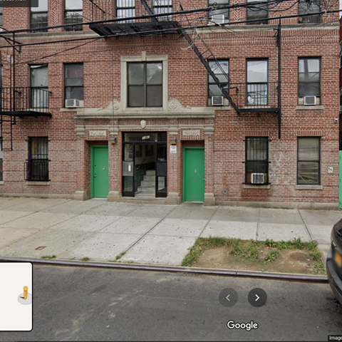 A red brick building with a green door and a balcony.