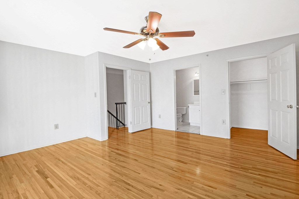 an empty living room with wood floors and a ceiling fan