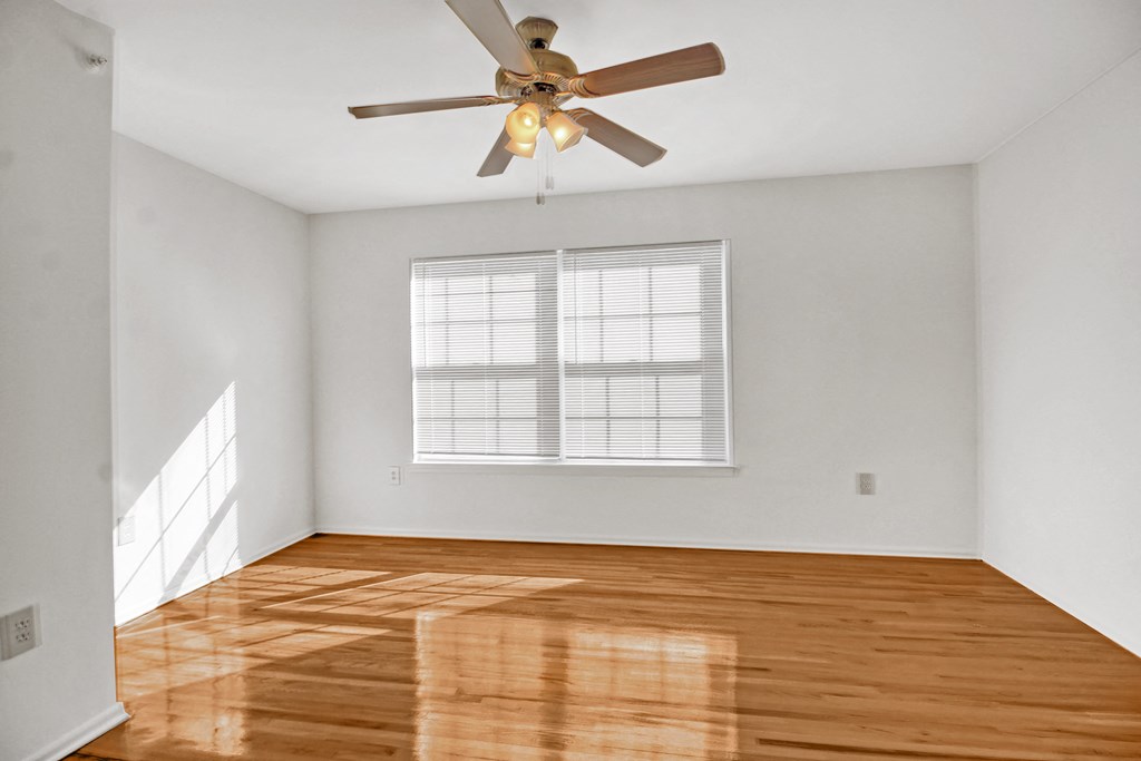 an empty living room with wood floors and a ceiling fan